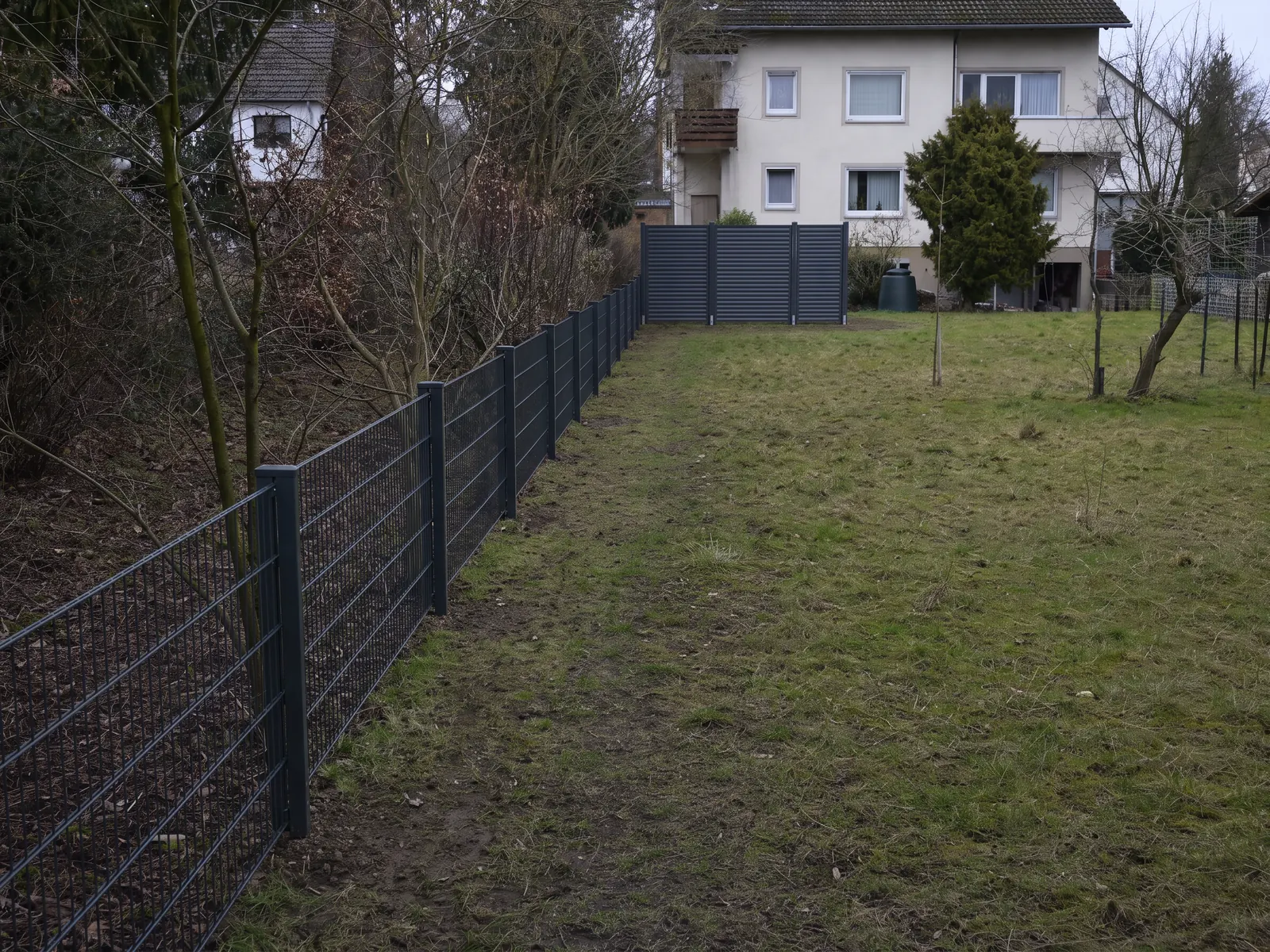 Dieselbe Grenze mit lotrecht gesetztem Zaun und Sichtschutzelementen